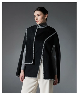 Detail of black poncho shawl showing contrast white stitching and premium fabric texture