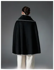 Detail showing high-quality black wool poncho cape with white contrast stitching on the edges