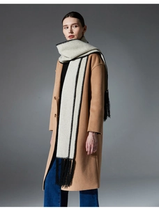 Close-up of oatmeal wool scarf featuring black hand-stitched edges and long tassels