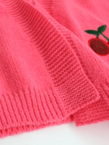 Detailed close-up of fuchsia knit cardigan featuring delicate cherry embroidery