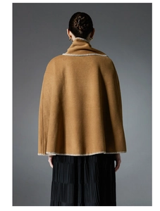 Macro detail of camel wool cape showing high collar and white hand-stitched decorative seams