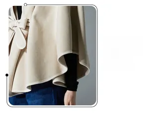 Detail of beige hooded shawl cloak featuring elegant white contrast piping and bow tie knot
