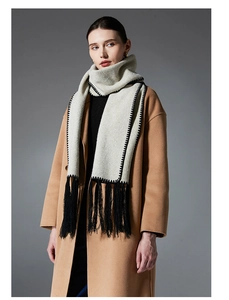 Close-up of light grey scarf with black tassel details and decorative stitching on a coat