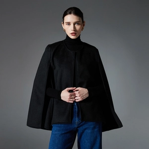 Elegant women's black wool-blend sleeveless cape coat styled with casual blue denim jeans