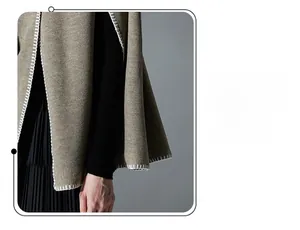 Detailed close-up of khaki knitted poncho featuring decorative white blanket stitch edging