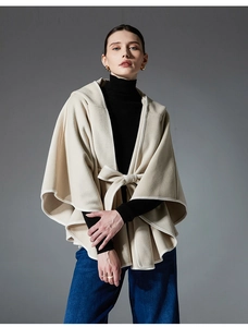 Detailed close-up of beige hooded cloak showing soft wool texture and waist tie bow