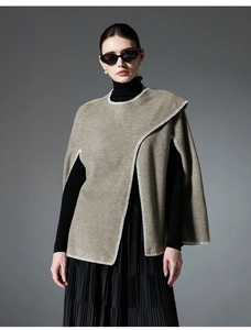 Detail view of double-faced stitching and textured fabric on light brown fashion poncho