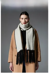 Detail view of beige wool scarf with contrast black stitching and long fringes on camel coat
