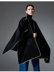 Detail of premium black wool cape with decorative white blanket stitch edging and draped fit