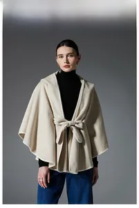 Detail of cream-colored hooded poncho with soft wool texture and bow tie closure
