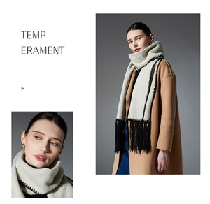 Detail of knit scarf with black contrast stitching and long tassels on beige wool