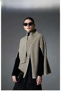 Detail of earthy-tone knit poncho featuring white blanket stitching and high-end texture