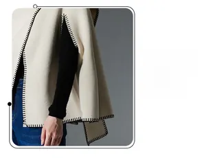 Detail of cream cape shawl featuring thick wool texture and black blanket stitching edges