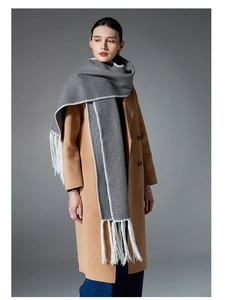 Detail view of gray winter scarf featuring contrast white stitching and long fringe tassels