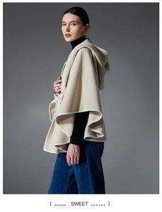 Close-up of beige hooded wool cape with refined edging and side lace-up details