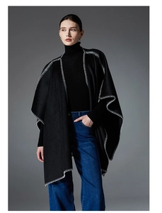 Detail of a black shawl featuring white manual blanket stitch edges and oversized silhouette
