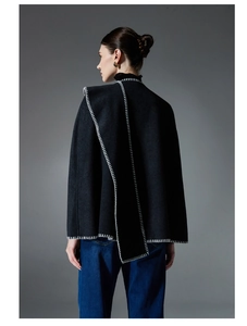 Detail of premium black wool cape with white contrast stitching on a studio model