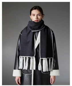 Detailed close-up of dark grey wool scarf with white zigzag stitching and long tassels