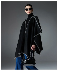 Detail of black wool cape featuring contrasting white blanket stitch and thick fabric texture