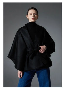 Détail d'un manteau poncho noir en laine avec ceinture à la taille et manches larges