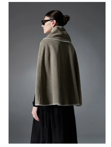 Detail of taupe knitted poncho featuring white contrast stitching and a high collar