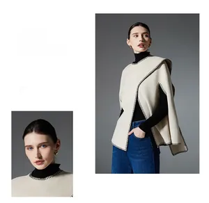 Detail of off-white knit poncho featuring contrast black blanket stitch edges and texture