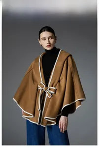 Detail of camel hooded cape coat with white contrast trim and elegant bow tie closure