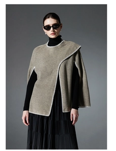 Detail of khaki knit poncho with white blanket stitching and asymmetrical wrap design