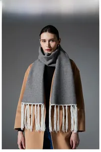 Detail of grey winter scarf featuring long white tassels and soft knitted texture