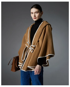 Detail of camel hooded wool cloak with white piping and waist tie bow detail