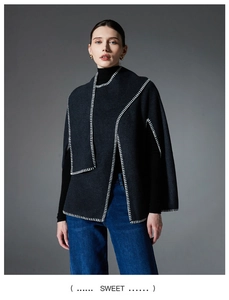 Detail shot of a charcoal wool cape with elegant white whipstitch contrast edging