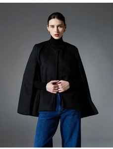 Elegant black sleeveless cape coat styled with denim jeans for a chic autumn outfit