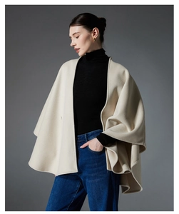 Detailstruktur eines beigen Wollcapes mit veredelten Kanten und elegantem Faltenwurf