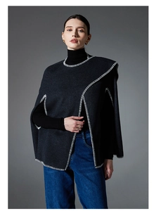 Detailed close-up of dark grey wool poncho with contrast white blanket stitch edge