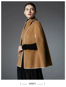 Detail of camel wool cape shawl with decorative white hand-stitched embroidery edges