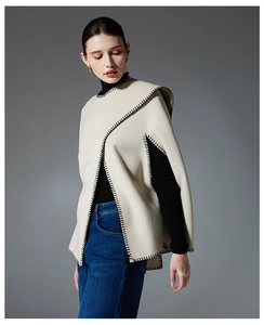 Detail showing high-quality beige wool poncho with decorative black blanket stitching edges