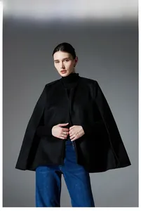 Detail of elegant black wool cape coat paired with a turtleneck for a stylish autumn look