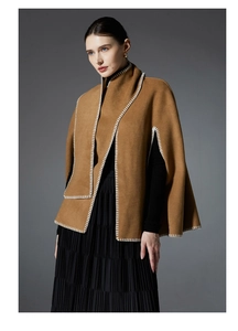 Detail of camel wool poncho showing white blanket stitch edges and textured wool fabric