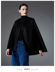 Detail of a chic black sleeveless cape coat with a decorative gold round button accent