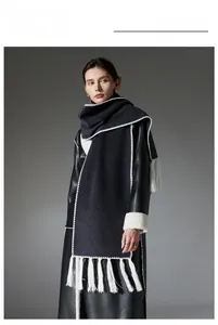 Detail of dark grey scarf with white decorative stitching and long fringe tassels