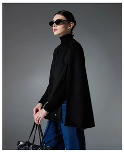 Detail shot of a black wool-blend cape coat with split sleeves and a round neckline