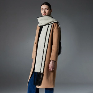 Beige wool scarf with black embroidery and tassels paired with camel coat and jeans