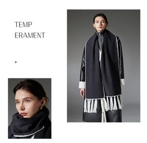 Detail of dark grey scarf with white zigzag stitching and long fringe on black leather coat