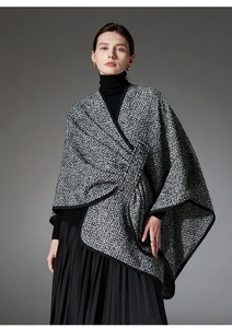 Detail of black and white boucle textured wool poncho with knitted edge for winter