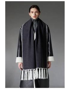 Detail view of deep grey wool scarf with white embroidery and long tassel edge design