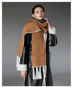 Detail of camel wool scarf with white stitching and long fringes worn with black coat