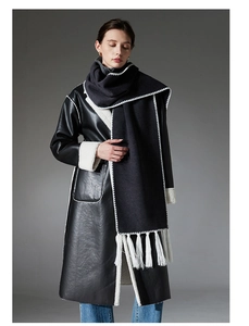 Detail of black faux leather coat with white shearling trim and long fringed scarf