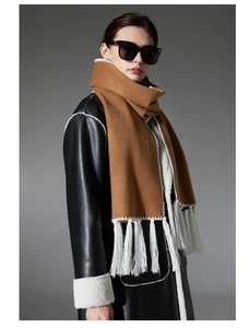 Detail of camel wool scarf featuring contrasting white thick tassels for winter fashion