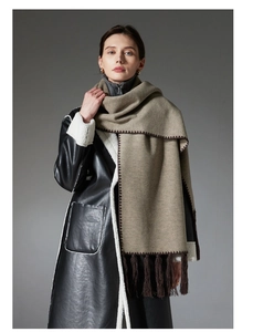 Detail of coffee brown cashmere scarf with bold stitching and fringe on leather coat