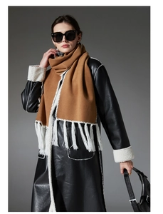 Detail view of camel scarf with white stitching, long fringes and black leather coat